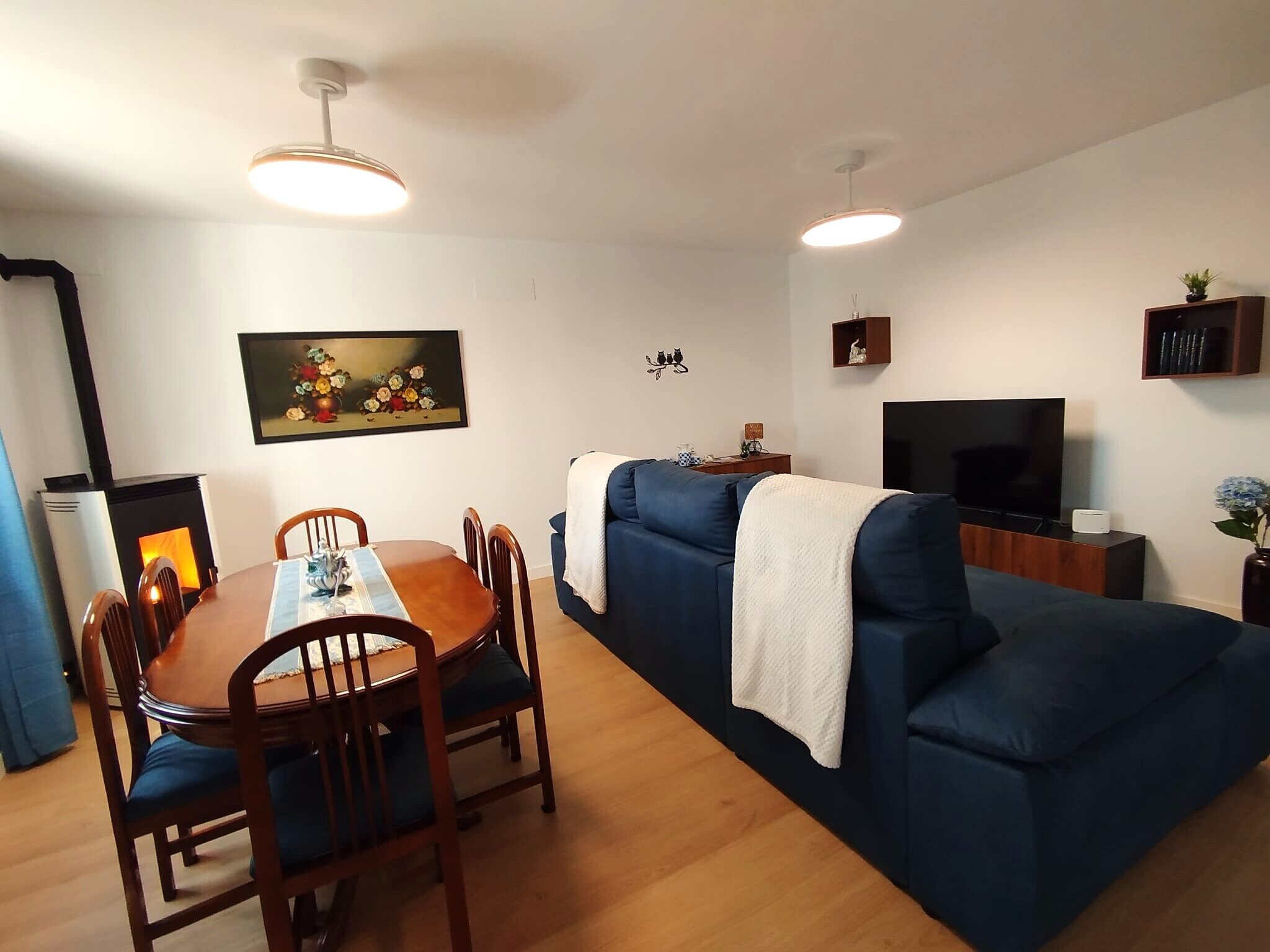 A living room with a dining table, blue sofa, TV, and fireplace.