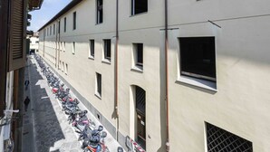 Eine schmale Straße gesäumt von abgestellten Motorrädern und Gebäuden mit einheitlicher Architektur.