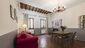 Ein Essbereich mit Tisch und Stühlen, einem roten Sofa, einer Chandelierleuchtre und einem wandmontierten Weinkühlschrank.