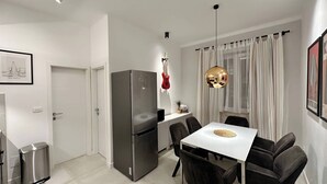 A modern kitchen with a stainless steel refrigerator, a dining table with four chairs, and a pendant light. - Vibehaus Center of Split City Only 400m From Beach (Split)