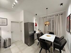 A modern kitchen with a stainless steel refrigerator, a dining table with four chairs, and a pendant light. - Vibehaus Center of Split City Only 400m From Beach (Split)