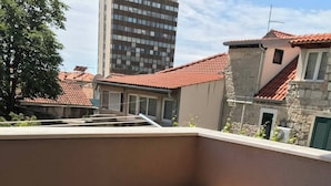 A balcony with a wooden table and two chairs, a stone wall, and a view of neighboring buildings. - Vibehaus Center of Split City Only 400m From Beach (Split)