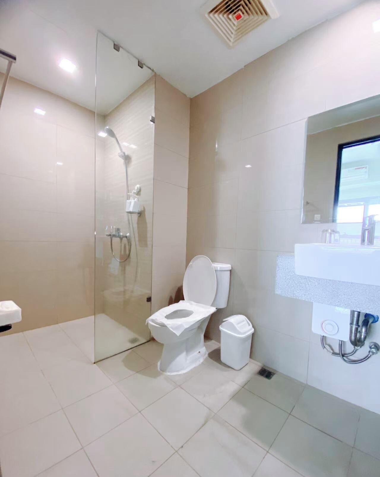 Een moderne badkamer met een douchecabine van glas, een wit toilet en een wastafel met een spiegel erboven.