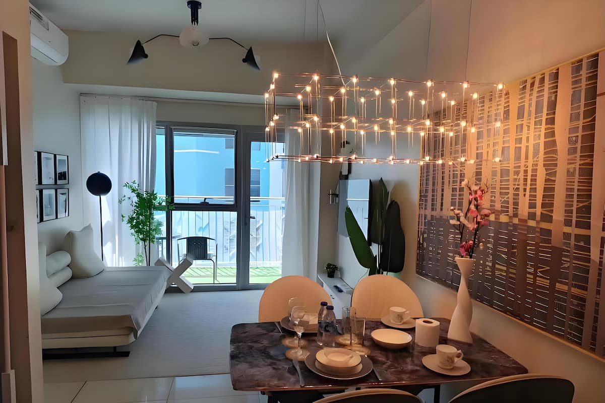 Un comedor moderno con una mesa lista para dos, un sofá y un balcón con vistas.