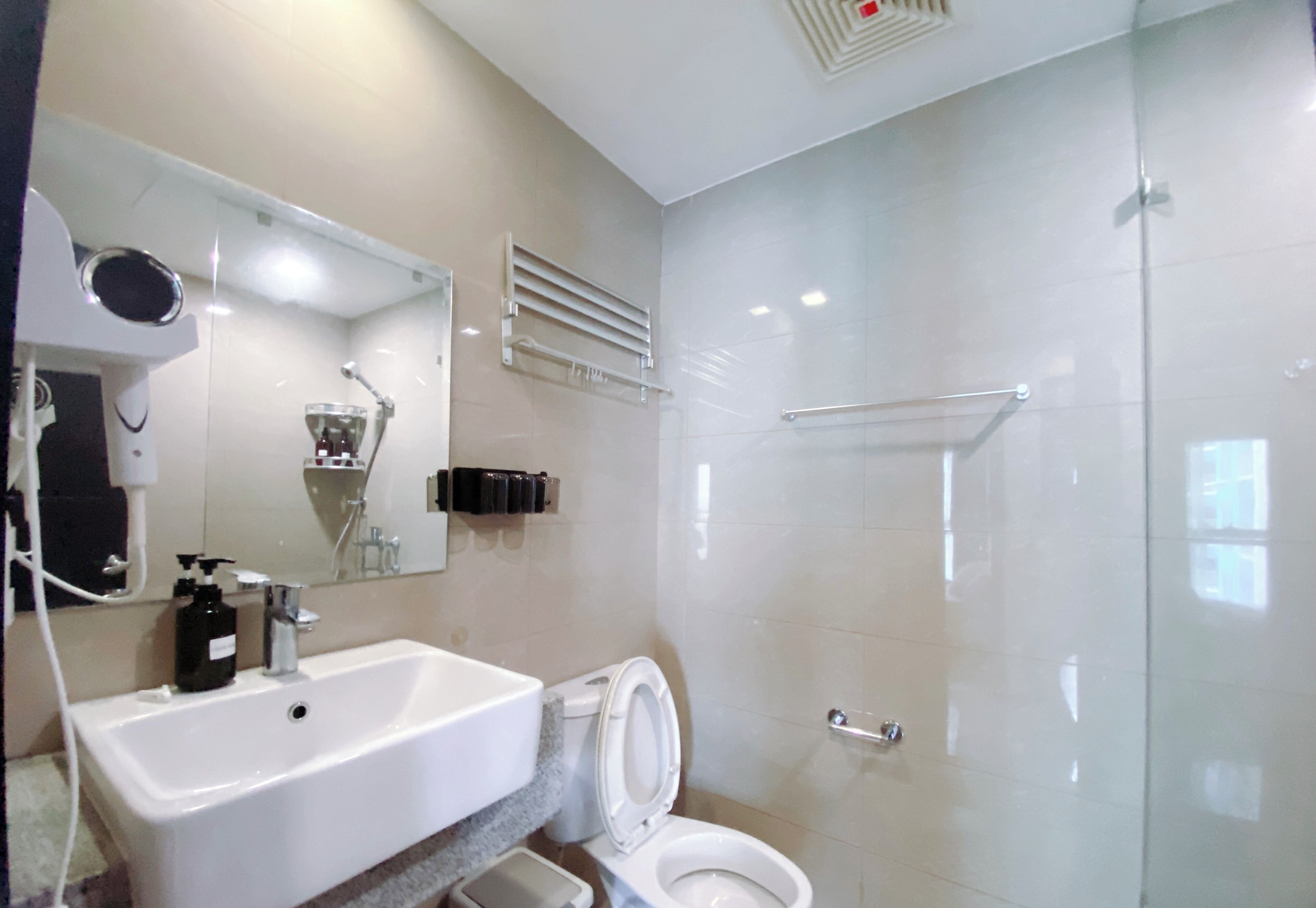 A modern bathroom with a white sink, toilet, and glass shower enclosure.