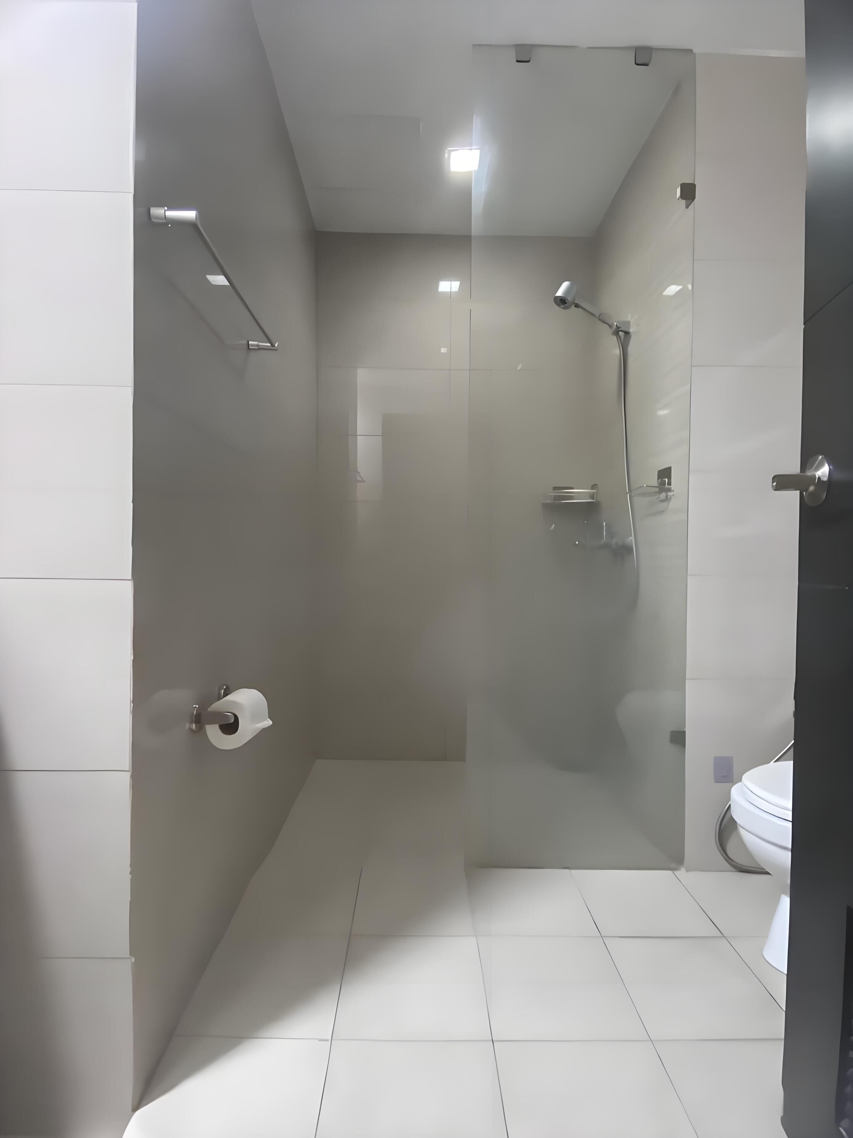 Ein modernes Badezimmer mit einer gläsernen Duschkabine, einer Toilette und einem Handtuchhalter.