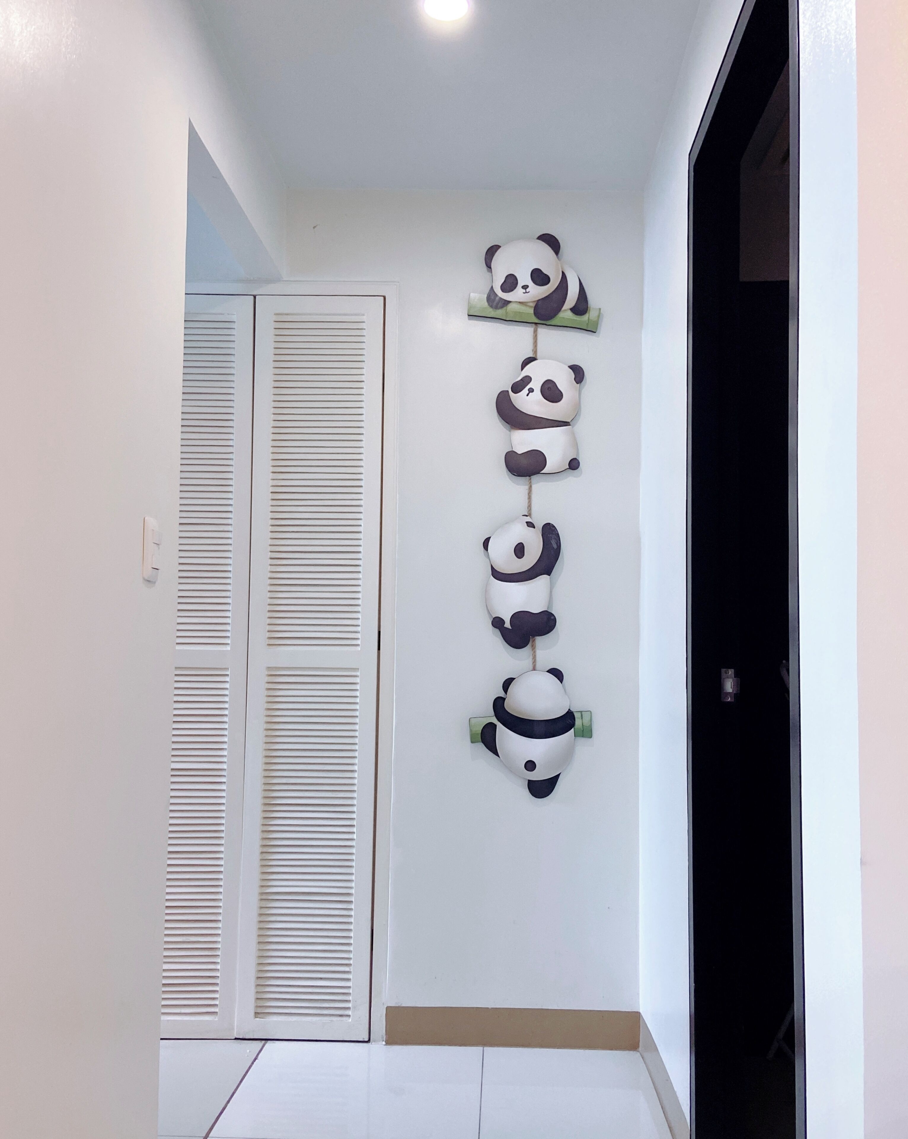 A hallway with a white door and a wall-mounted panda decoration.