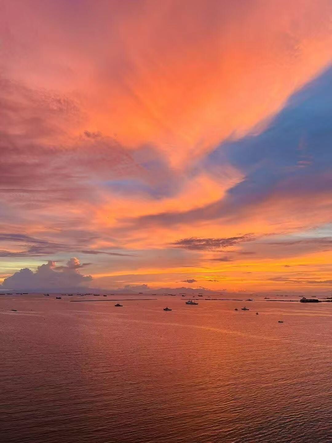 A sunset over a calm sea with boats.