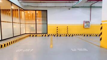 Un espacio interior amplio con una barrera rayada en amarillo y negro, divisiones de vidrio y un techo con tuberías a la vista.