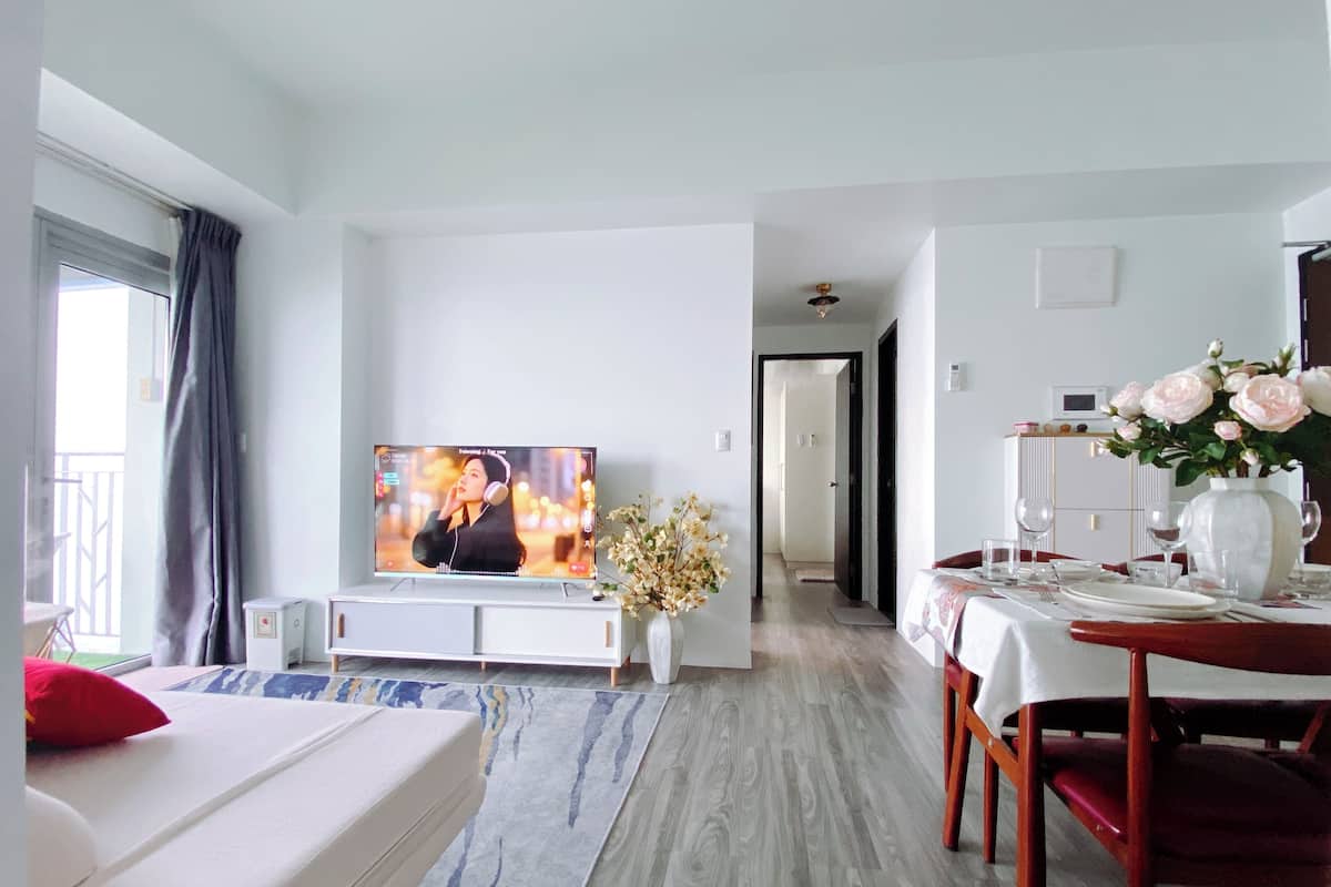 Una habitación de hotel moderna con televisión, zona de comedor y vistas al exterior.