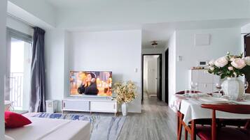 Una habitación de hotel moderna con televisión, zona de comedor y vistas al exterior.