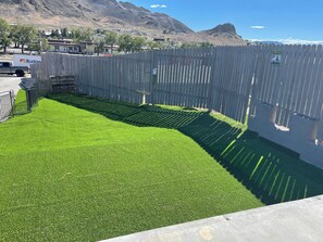 A fenced area with artificial grass, a wooden fence, and a mountain backdrop. - Dream Inn  (Tonopah)