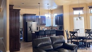 A living room with a leather sofa, a dining area with a table and chairs, a kitchen with dark cabinets and a refrigerator, and a ceiling fan. - `Live Like a Local, Stay Like a Guest` (Oklahoma City)