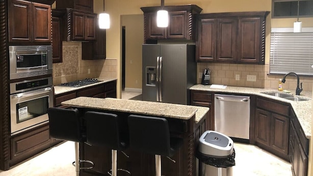 A modern kitchen with dark wood cabinets, stainless steel appliances, a granite countertop, and pendant lighting. - `Live Like a Local, Stay Like a Guest` (Oklahoma City)