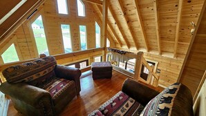 A wooden cabin with a loft bedroom, a balcony with a railing, and a view of the outdoors. - Grand Magnolia Cabin (Rock Island)