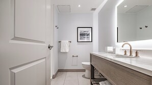 A modern bathroom with a wooden vanity, a large mirror, and a framed picture on the wall. - Hotel Bridgton (Bridgton)