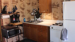 A kitchen with wooden cabinets, a stove, a microwave, and a sink.
