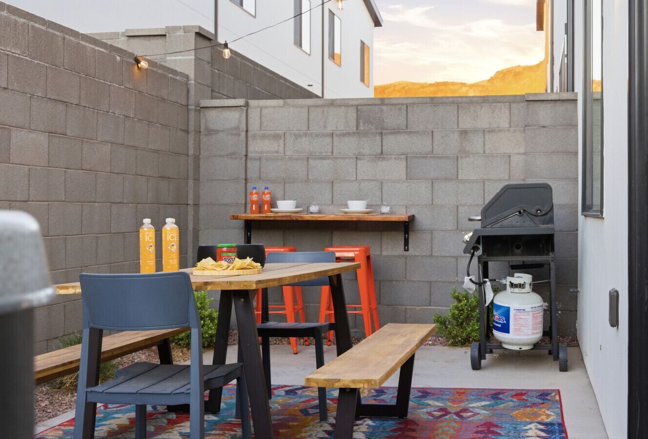 Une terrasse extérieure avec une table, des chaises et un barbecue.