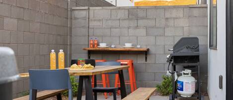 Une terrasse extérieure avec une table, des chaises et un barbecue.