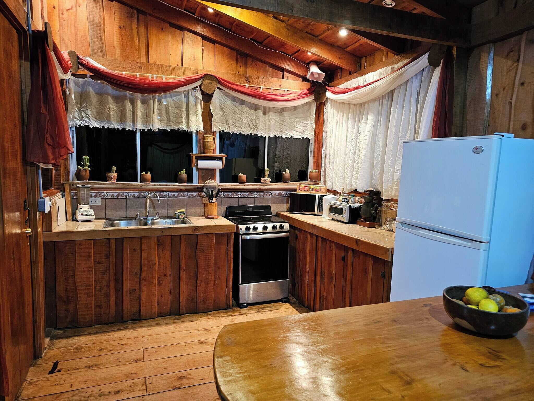 Una cucina rustica con mobili in legno, un fornello, un lavello e un frigorifero.
