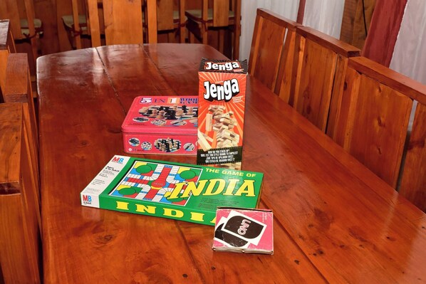 A wooden table with a board game, a Jenga box, and a deck of UNO cards.