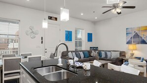 Una cocina moderna con encimera de granito, pileta de acero inoxidable y ventilador de techo.