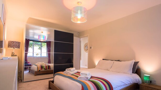 Ein Schlafzimmer mit Bett, Nachttisch und Spiegel.