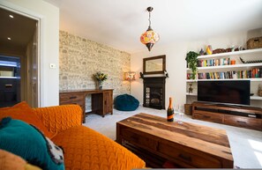 A living room with a sofa, coffee table, fireplace, bookshelf, and television. - Elegant 1-bed Flat in a Georgian Townhouse (London)