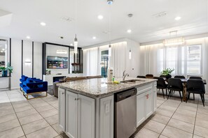 A modern kitchen with a large island, built-in appliances, and a dining area with a table and chairs. - Family-Friendly Villa with Pvt Pool, BBQ, Game Room & Themed Bedrooms (Davenport)