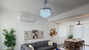 Un soggiorno moderno con un divano angolare grigio, un tavolino in legno e una zona pranzo con tavolo e sedie in legno.