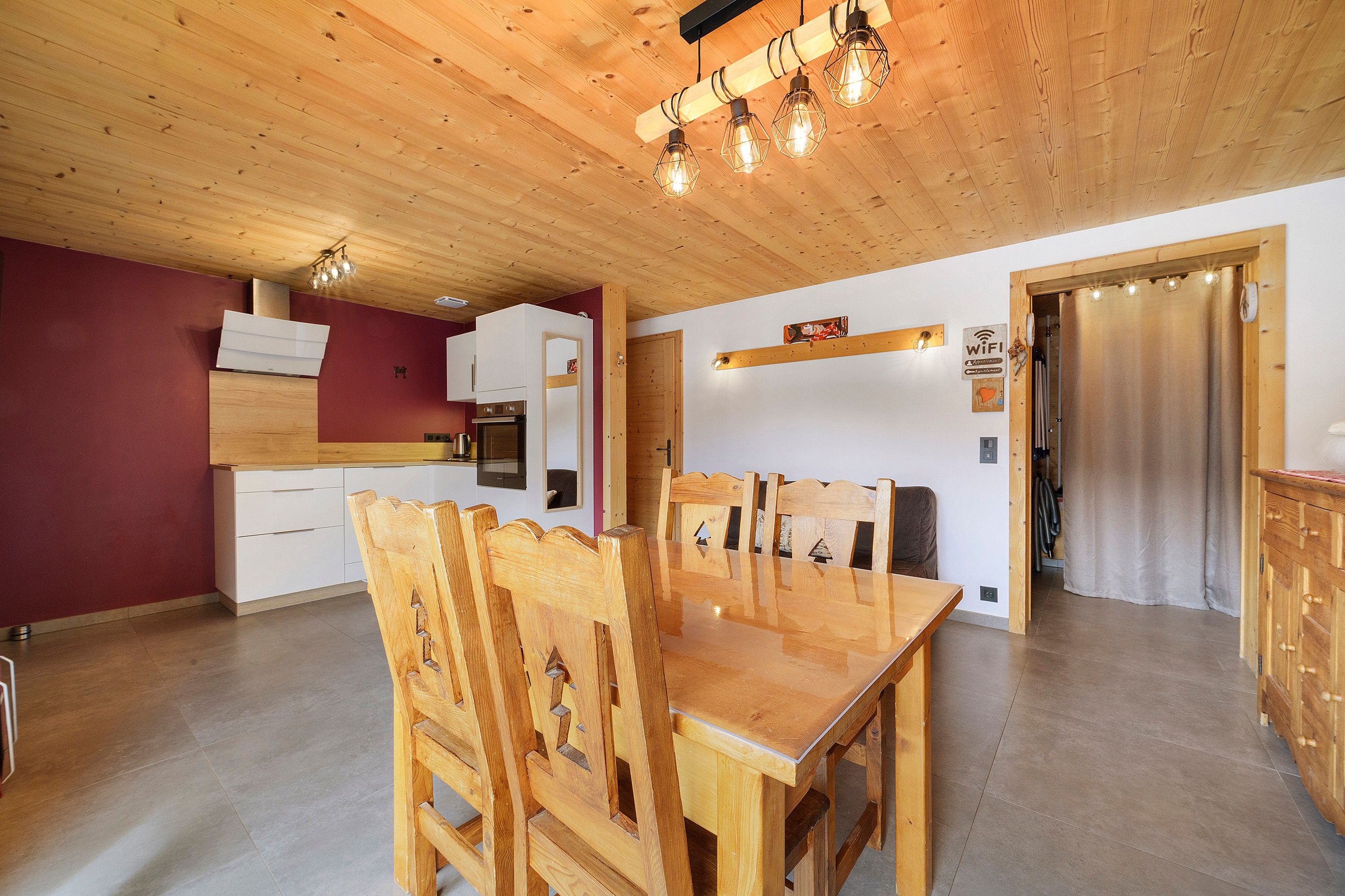 A modern kitchen with wooden cabinetry, a dining area with a wooden table and chairs, and a visible WiFi sign.