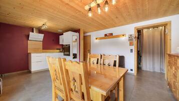 A modern kitchen with wooden cabinetry, a dining area with a wooden table and chairs, and a visible WiFi sign.