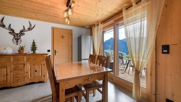 Een houten interieur met een eettafel, stoelen, een kast en een aan de muur bevestigd decoratie van een hertenkop.