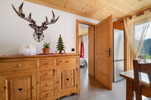 A wooden interior with a cabinet, a decorative wall piece, a small potted plant, and a view through an open door. - Holiday Home 'New in Detached Chalet' with Private Terrace and Wi-Fi (Châtel)