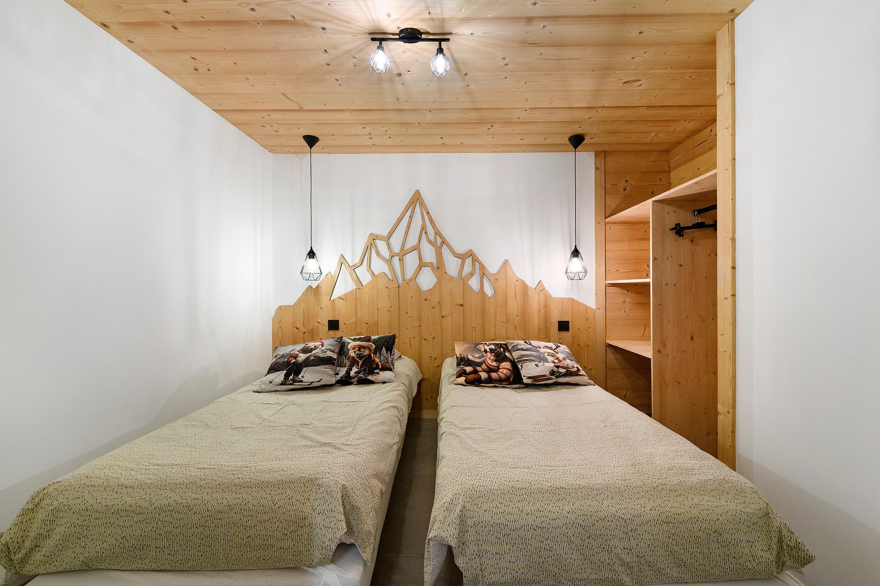 Ein Schlafzimmer mit zwei Betten, einem Holzkopfteil und Pendelleuchten.