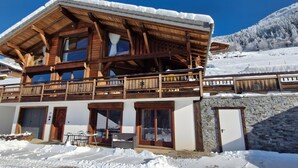 Eine Holzhütte mit Balkon, großen Fenstern und einer Steinwand.