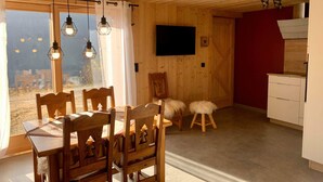 Ein Holzinnenraum mit Essbereich, Küche und einem an der Wand befestigten Fernseher.