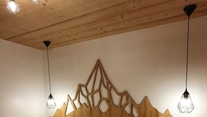 Ein Schlafzimmer mit einem hölzernen Kopfteil, einer gemusterten Bettdecke und drei Pendelleuchten.