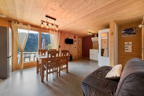 A wooden interior with a dining area, a sofa, and a view through the window. - Holiday Home 'New in Detached Chalet' with Private Terrace and Wi-Fi (Châtel)