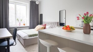 A modern bedroom with a bed, bedside table, and a window with curtains. - Stylish Studio in the Heart of Kallio (Helsinki)
