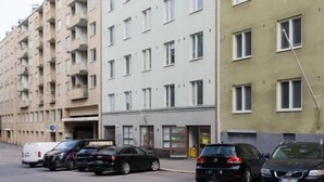 A multi-story residential building with a row of parked cars in front. - Stylish Studio in the Heart of Kallio (Helsinki)
