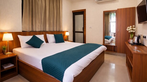 Une chambre d’hôtel avec un grand lit, des tables de chevet, une télévision, une armoire et un appareil de climatisation.
