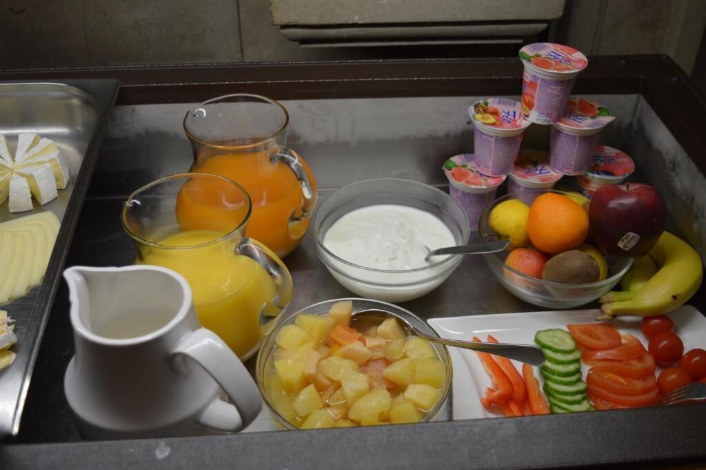 A breakfast buffet with various fruits, vegetables, and beverages.