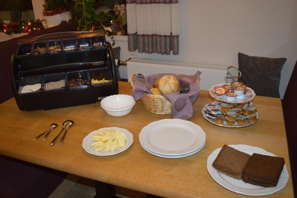 Een buffettafel met diverse soorten eten, zoals brood, gebak en een assortiment aan sauzen.