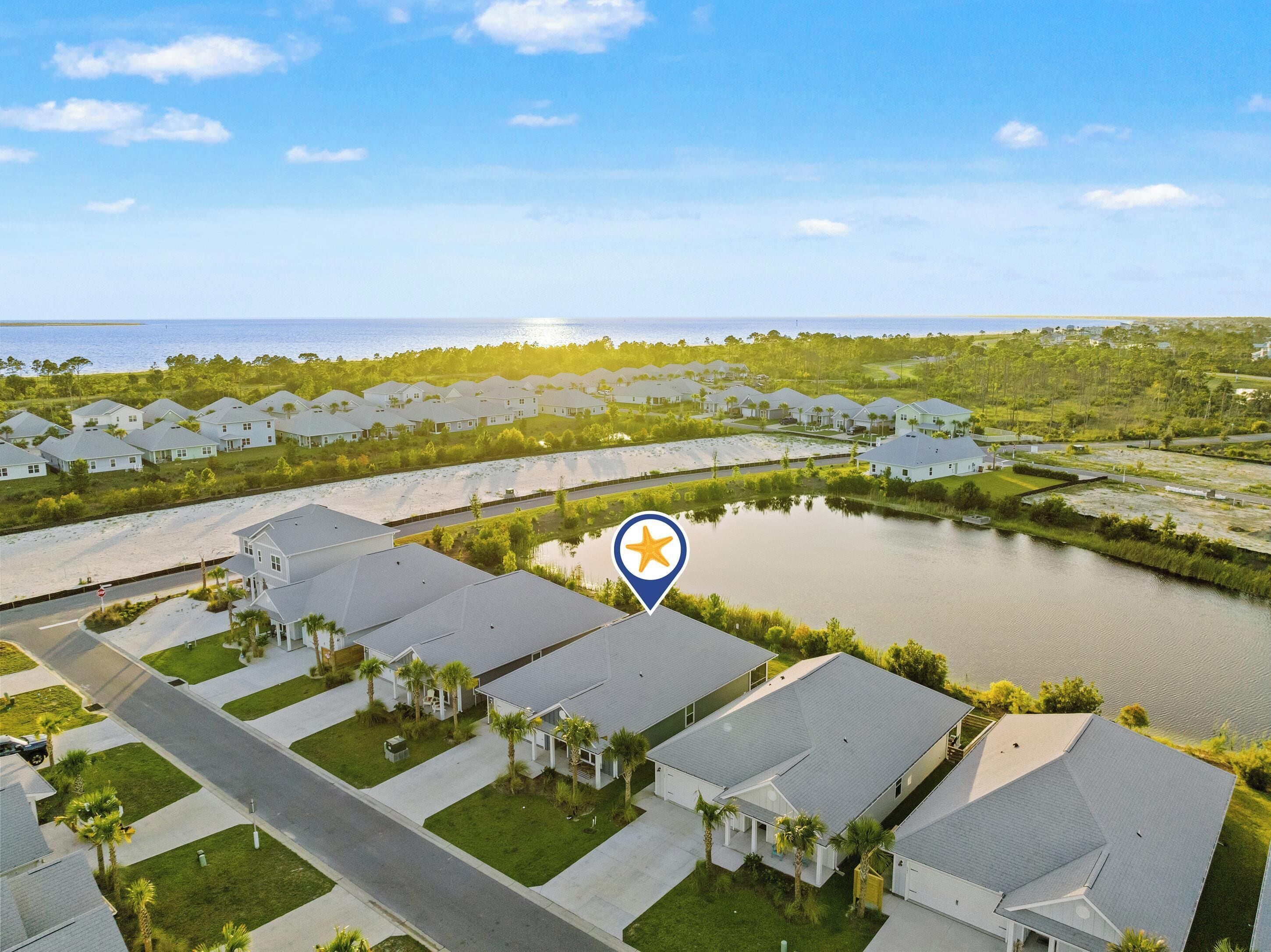 A residential area with houses, a body of water, and a clear sky.