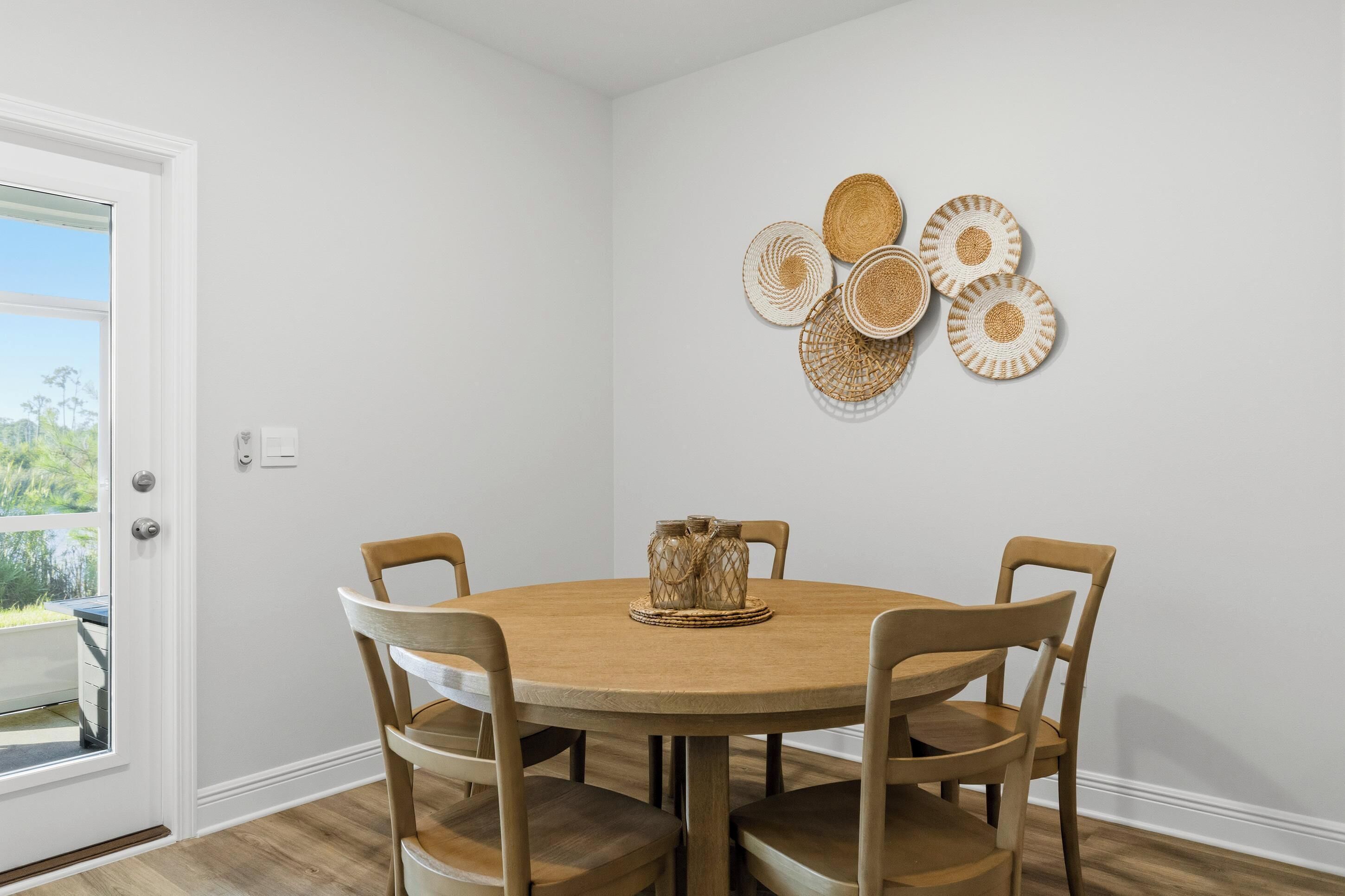 A dining area with a round table, four chairs, and a wall-mounted decorative item.
