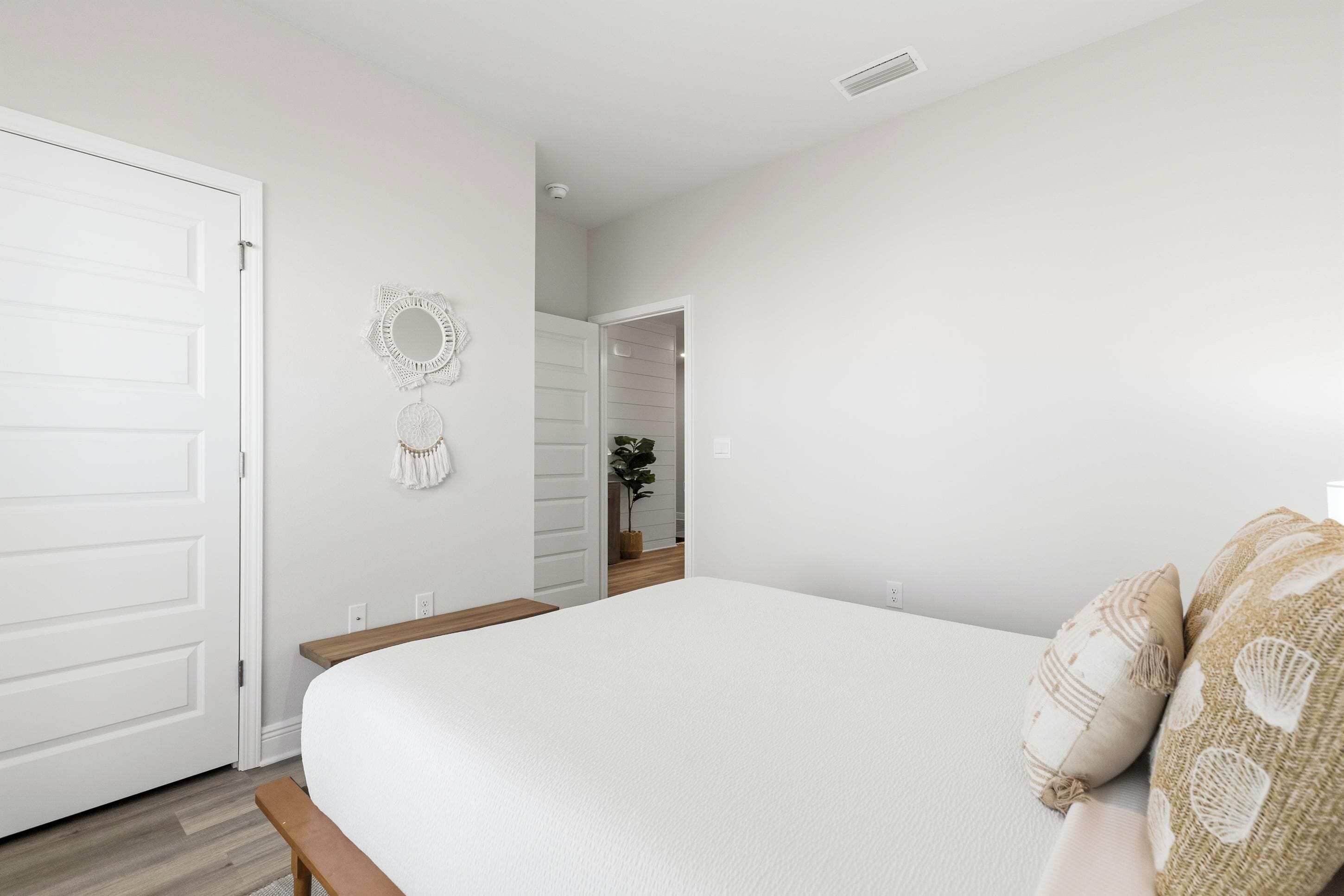 Un dormitorio con cama, una puerta, un adorno en la pared y un pasillo que lleva a otra habitación.