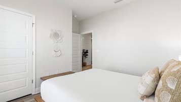 Un dormitorio con cama, una puerta, un adorno en la pared y un pasillo que lleva a otra habitación.