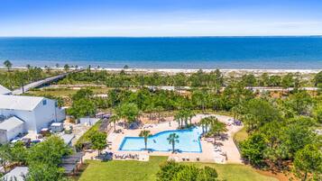 An aerial view of a resort with a swimming pool, beach access, and a large building.
