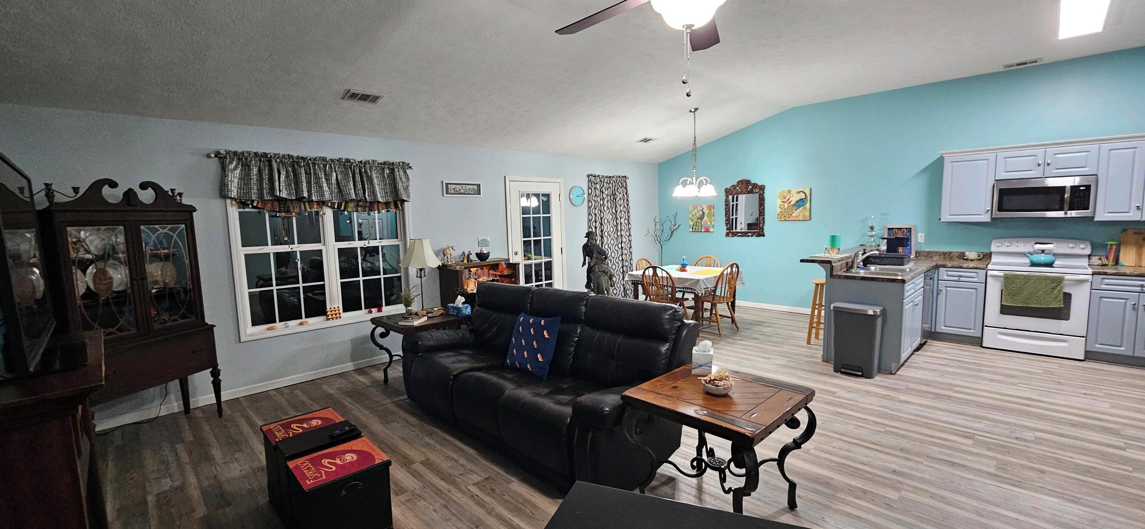 A living room with a black leather sofa, a wooden coffee table, and a dining area with a table and chairs.